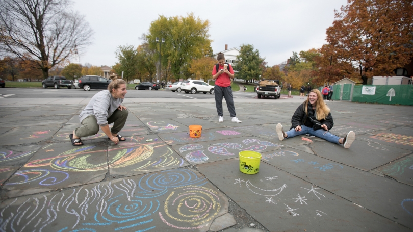 Students draw with sidewalk chalk.